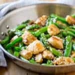 side shot of a pan with sesame chicken and sugar snap peas