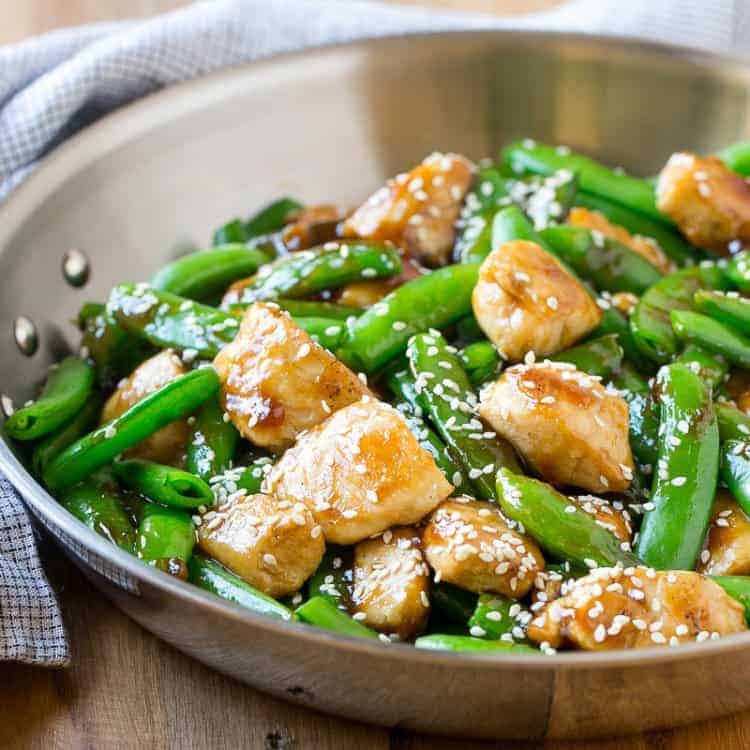 side shot of a pan with sesame chicken and sugar snap peas