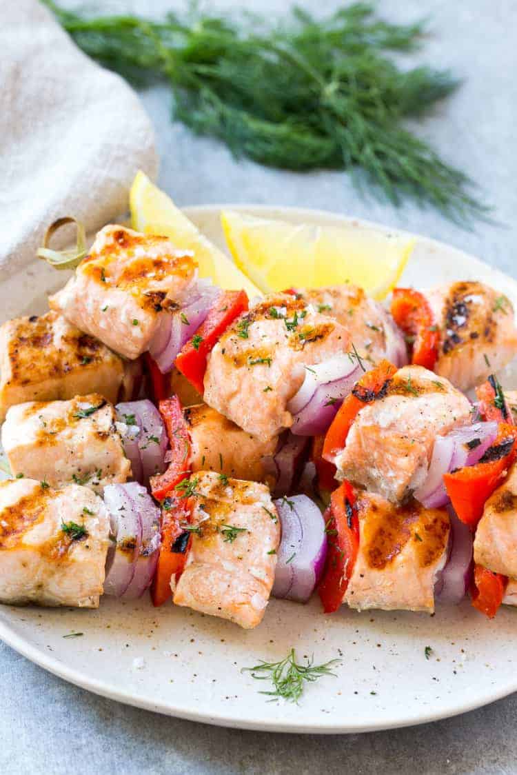 lemon dill salmon skewers on plate with lemon and veggies