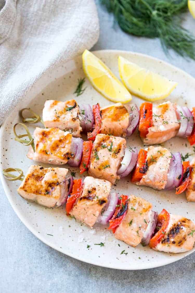 three Dill salmon kabobs on plate with veggies 