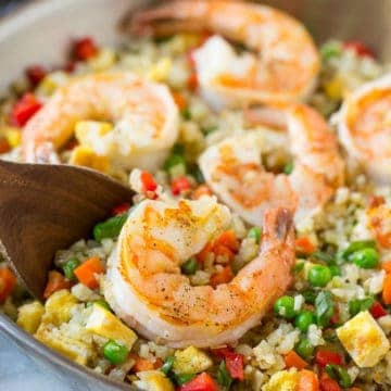 wooden spoon in skillet with shrimp and cauliflower rice