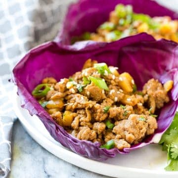 Asian cooked ground chicken in purple cabbage cups on a white plate