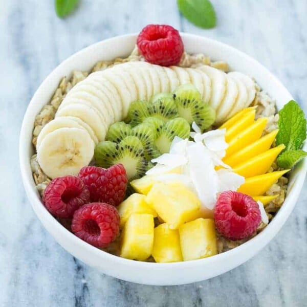 A dairy-free oatmeal topped with a variety of fresh fruit and coconut flakes.