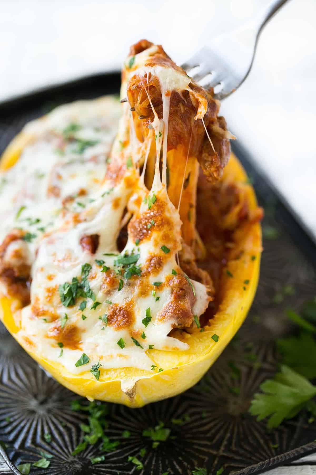 stuffed spaghetti squash on tray with fork grabbing a bite