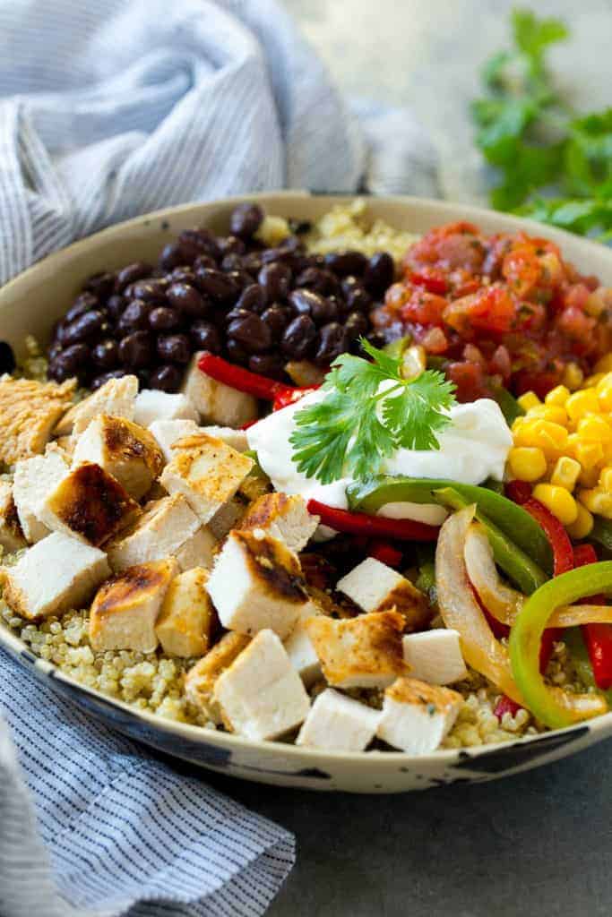 side shot of a quinoa bowl topped with grilled chopped chicken, black beans, corn, and salsa