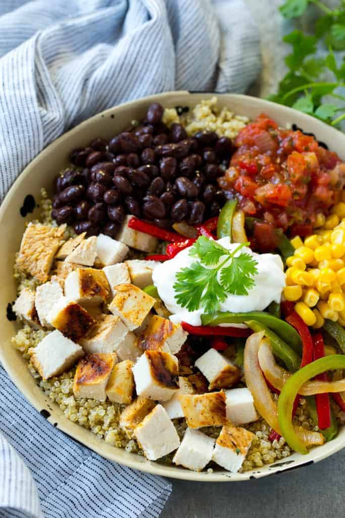 a bowl of quinoa and grilled chicken served with black beans, corn, and salsa 