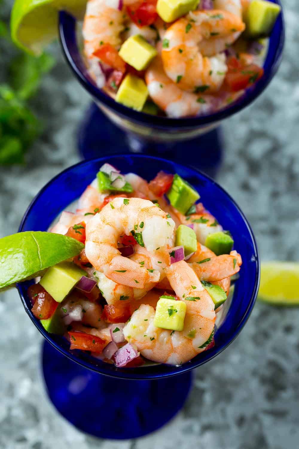 shrimp cocktail in two glasses with lime and avocado 