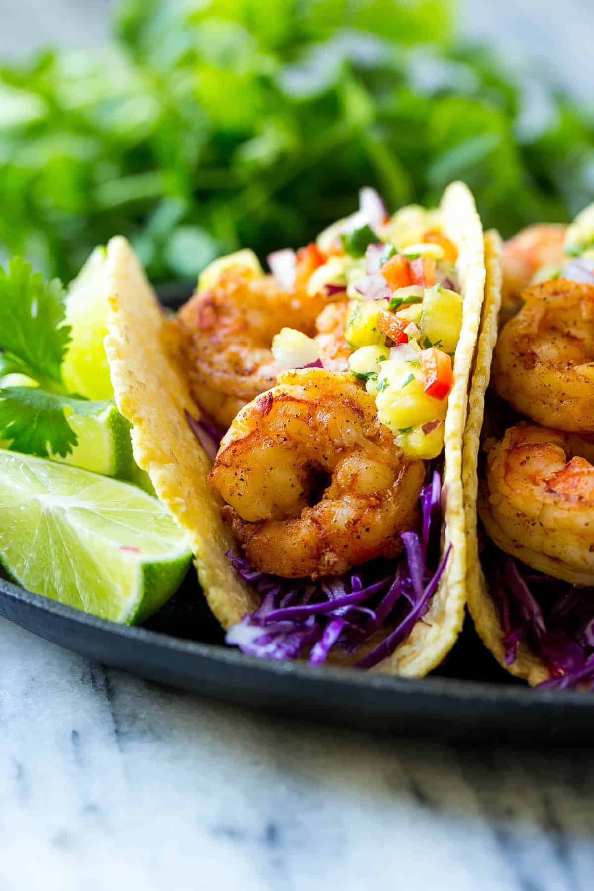 close view of shrimp taco on corn tortilla with lime and pineapple salsa