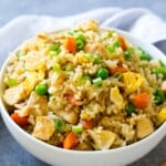 a round white bowl with chicken fried rice .