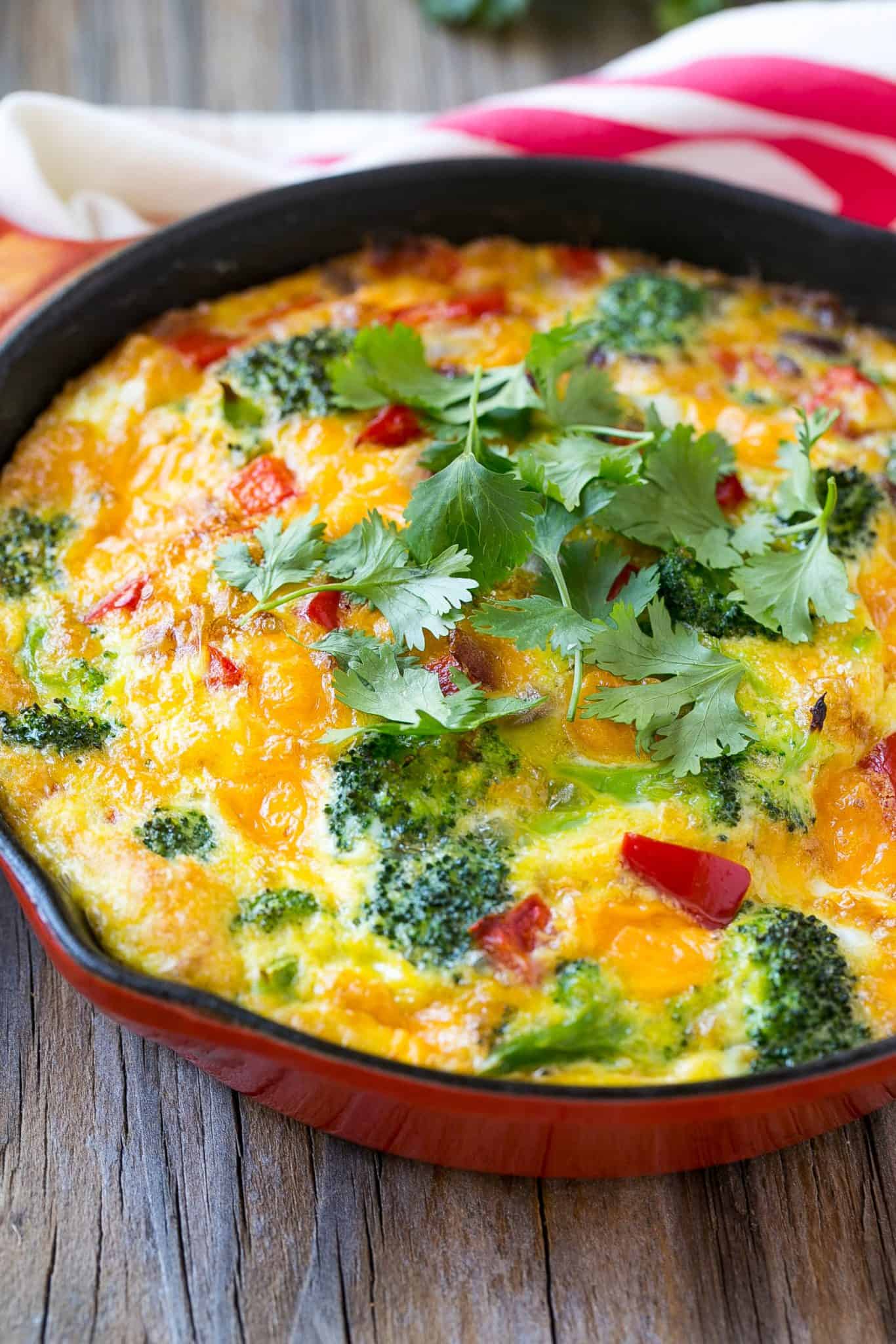 baked vegetable frittata skillet with cheese garnished with cilantro