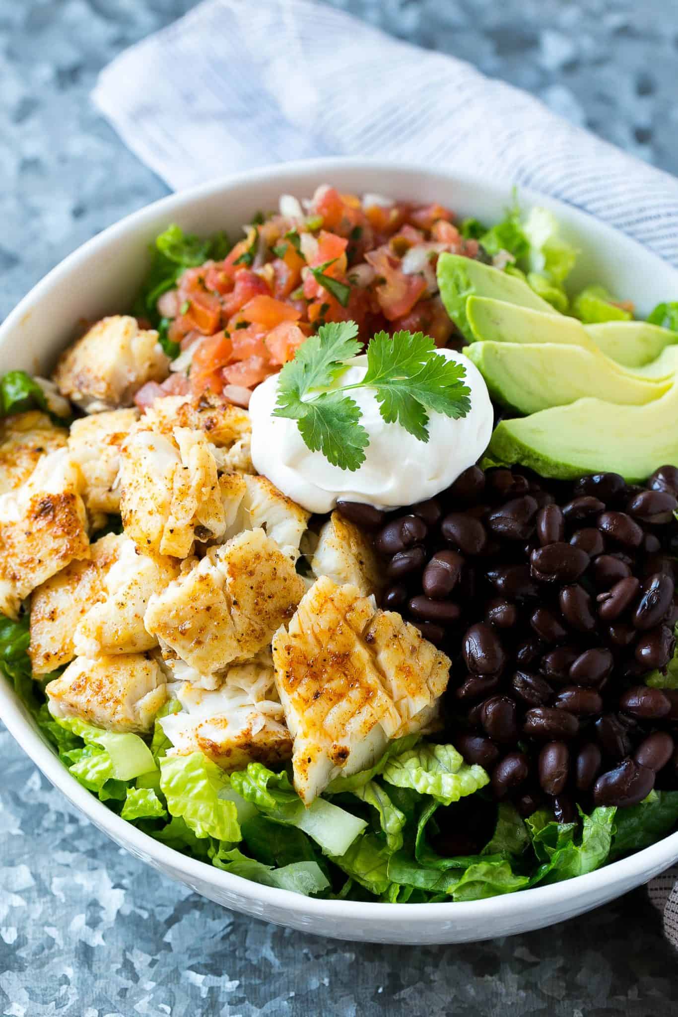 taco salad in white bowl with sour cream and cilantro