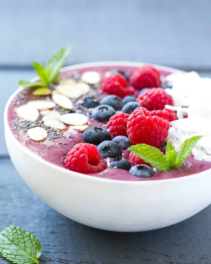 side shot of a smoothie bowl topped with berries and sliced almonds