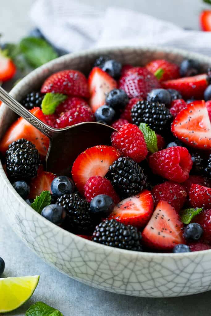 side shot of berry fruit salad in a bowl with spoon in bowl