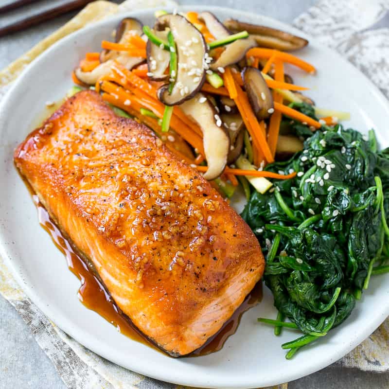 top view of pan seared salmon with side of veggies on a white plate