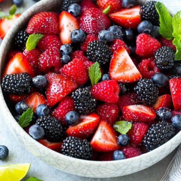Mixed Berry Fruit Salad in a white round bowl with mint and lime garnishes