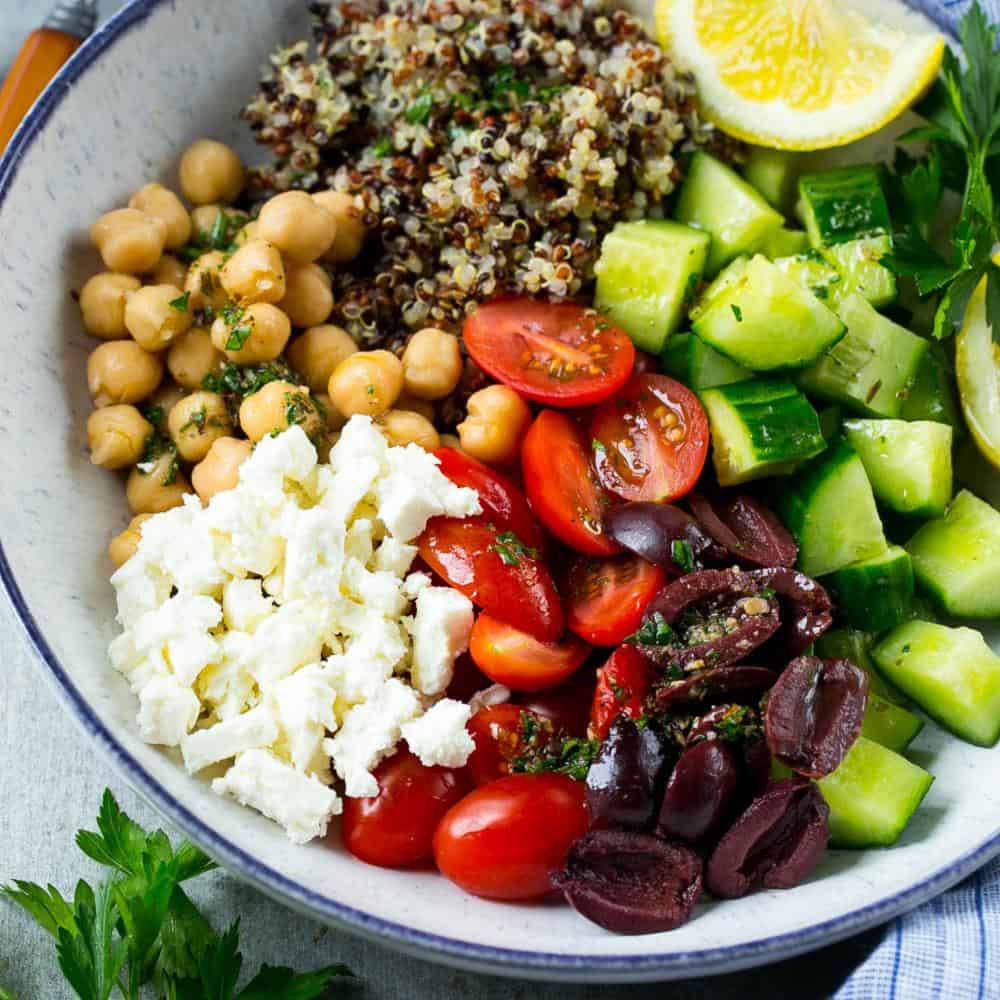 Greek Quinoa bowl in bowl with cucumbers and tomatoes