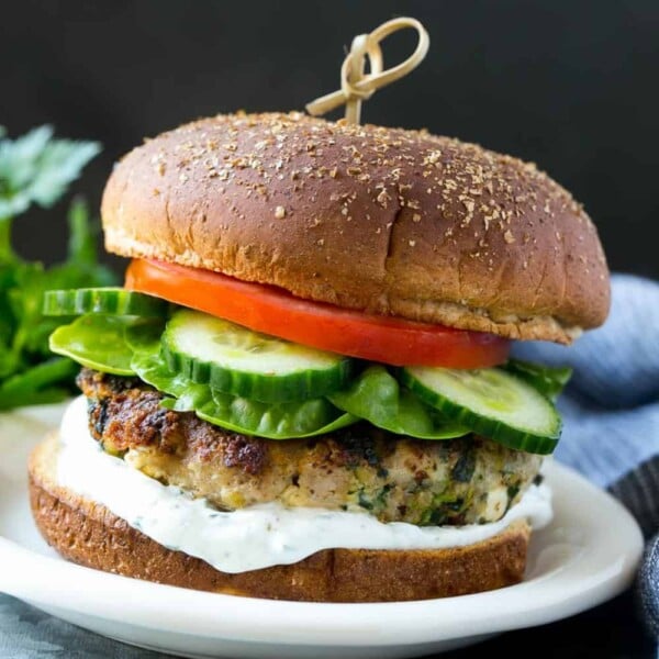 spinach feta turkey burger on white plate with cucumber, lettuce, and tomato