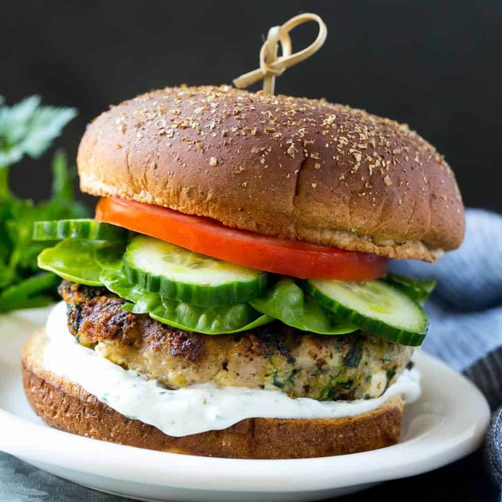 Spinach and Feta Turkey Burger on plate with lettuce, tomato, cucumber, and tzatziki sauce 