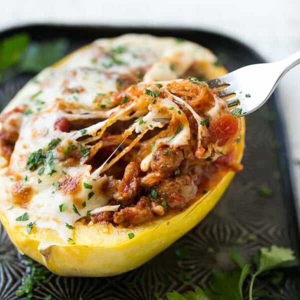 side shot of stuffed spaghetti squash with melted cheese and a fork grabbing a bite