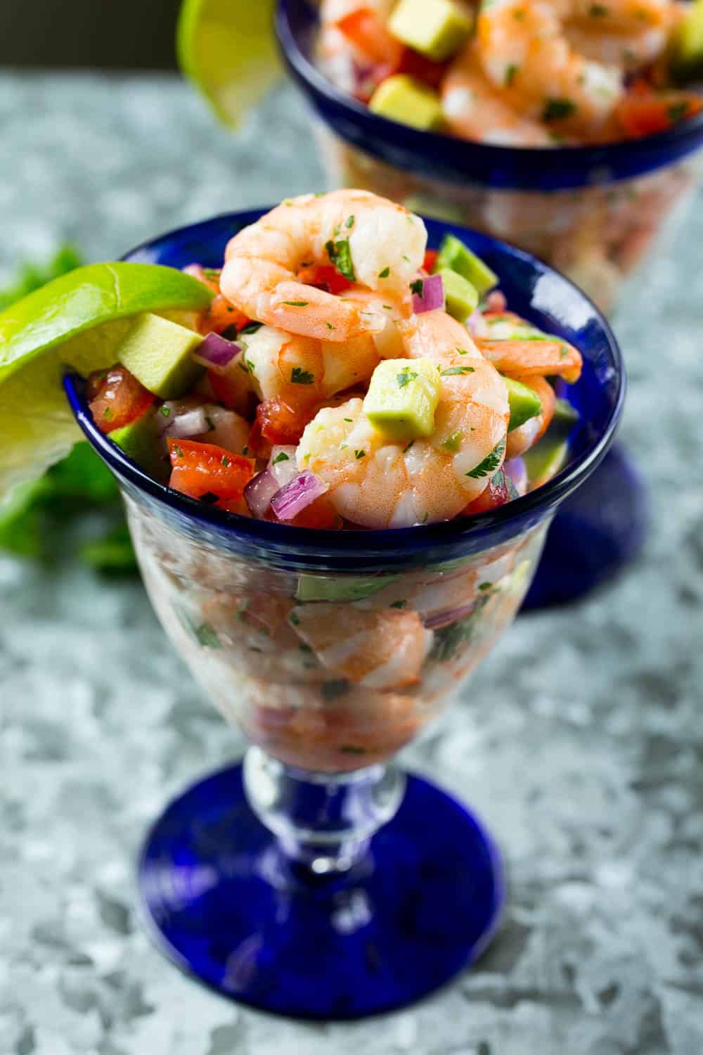 shrimp cocktail in glass with lime, cilantro, avocado, red onion 