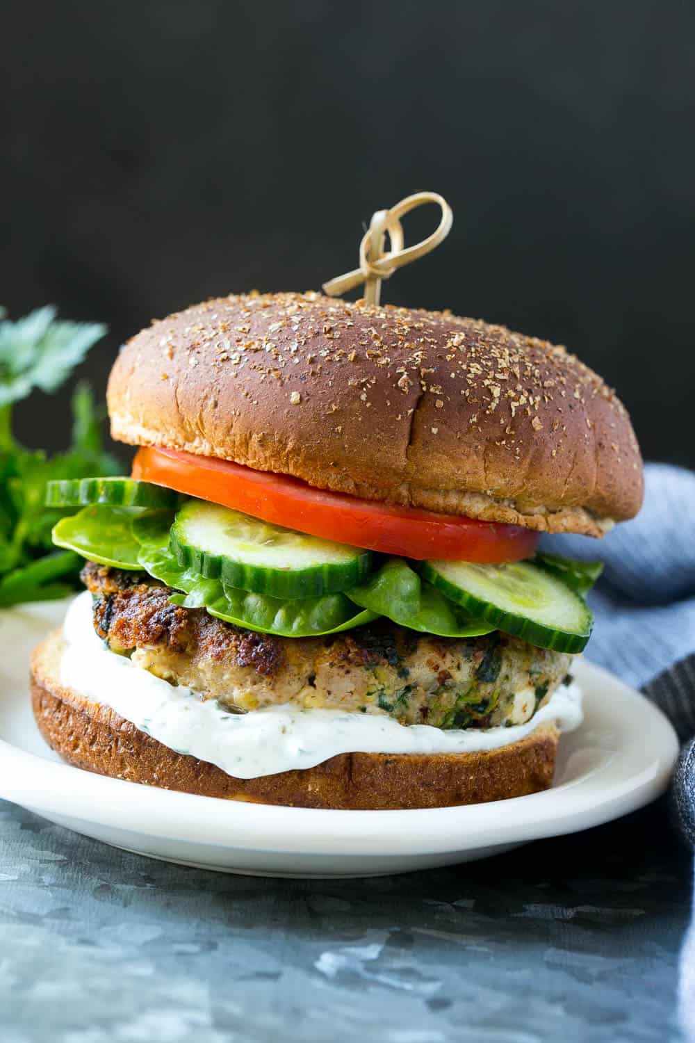 spinach and turkey feta burger on plate with cucumber, lettuce, tomato, and tzatziki sauce 