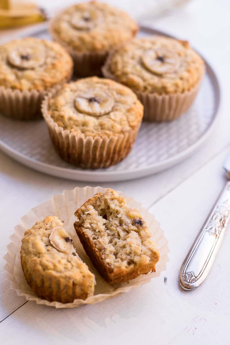 oatmeal muffins on a place in the back with one muffin cut in half towards the front