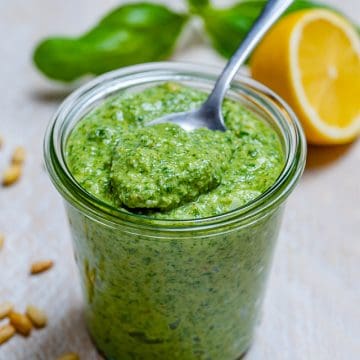 side shot of homemade pesto in a jar with a spoon full of pesto