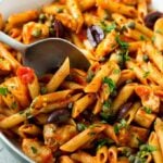 spoon in a pan with Chicken Pasta Puttanesca with kalamata olives and capers