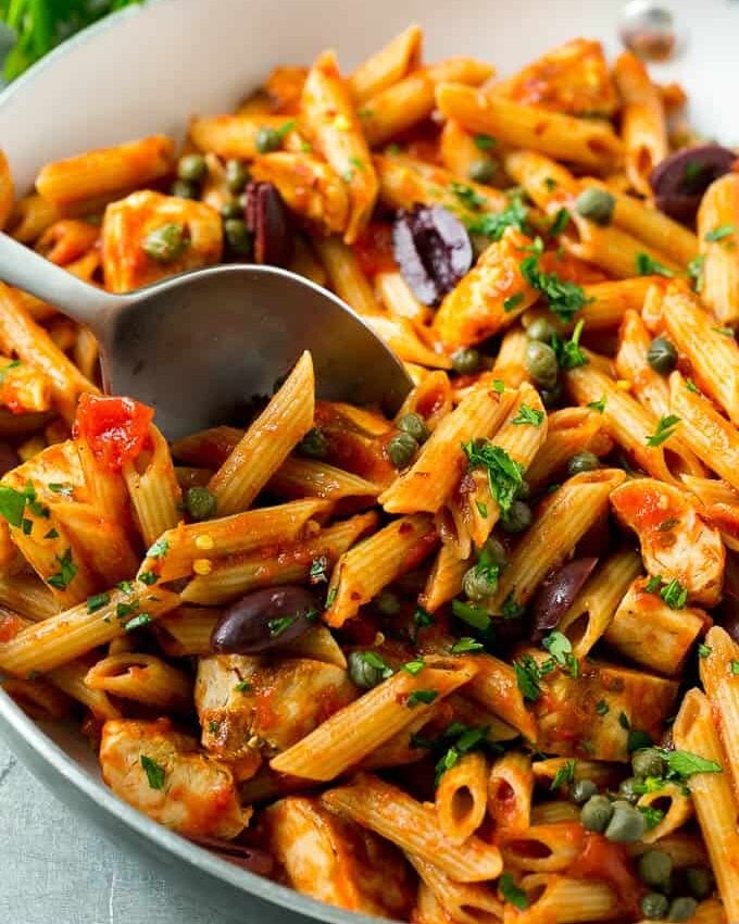 spoon in a pan with Chicken Pasta Puttanesca with kalamata olives and capers 