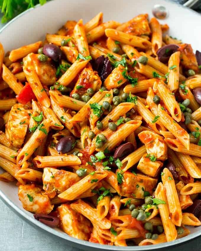 tomato-based pasta in a skillet made with penne pasta and kalamata olives