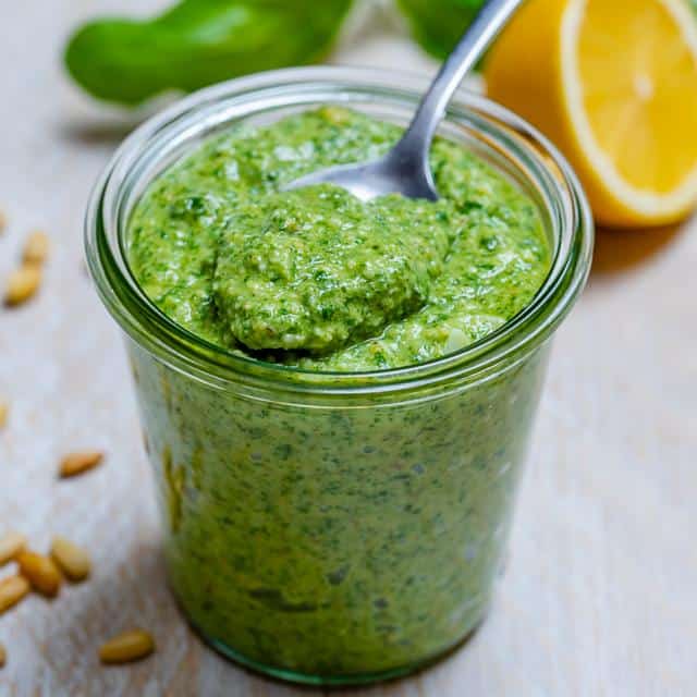 jar of green homemade pesto with spoon full of pestp
