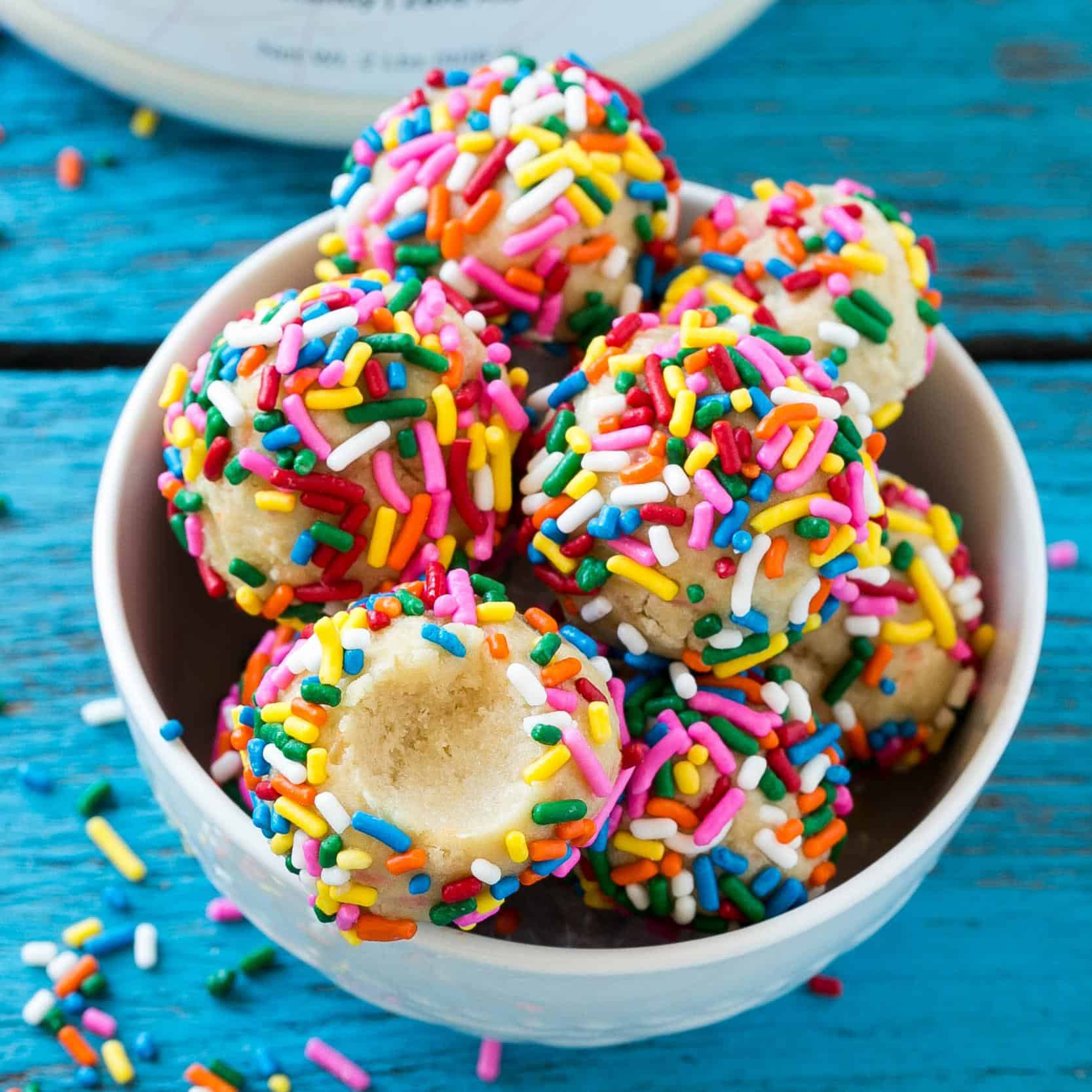 no bake birthday cake protein bites in white bowl with sprinkles 