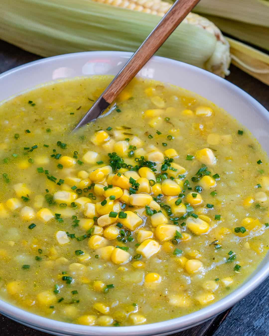 corn chowder soup in a pot with a wooden spoon in the pot.