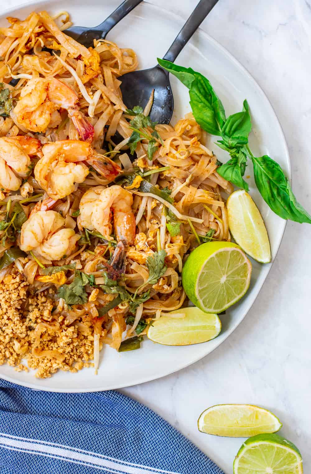 Pad thai on a plate with serving spoons