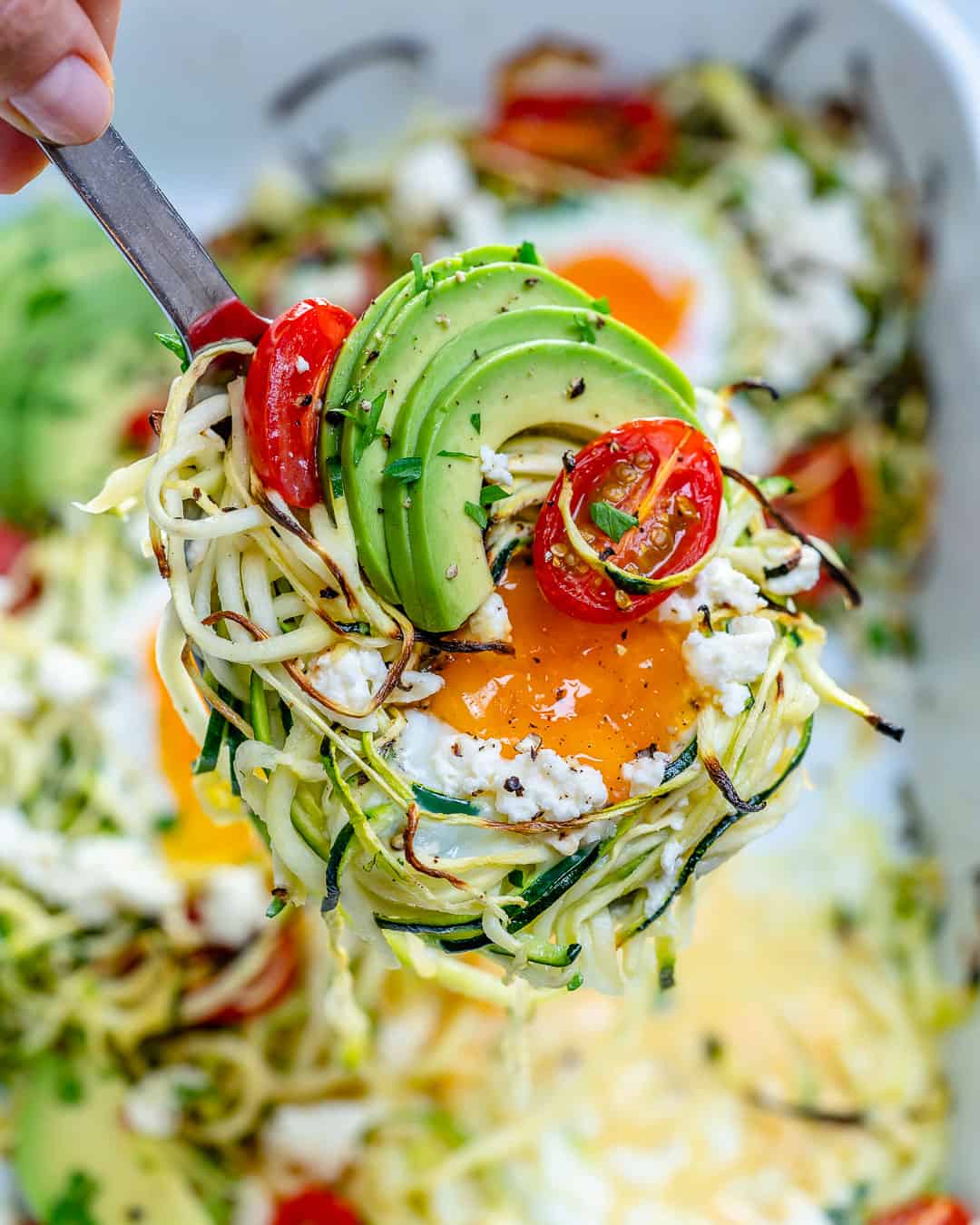 hand holding spatula with a portion of baked zoodles and eggs.