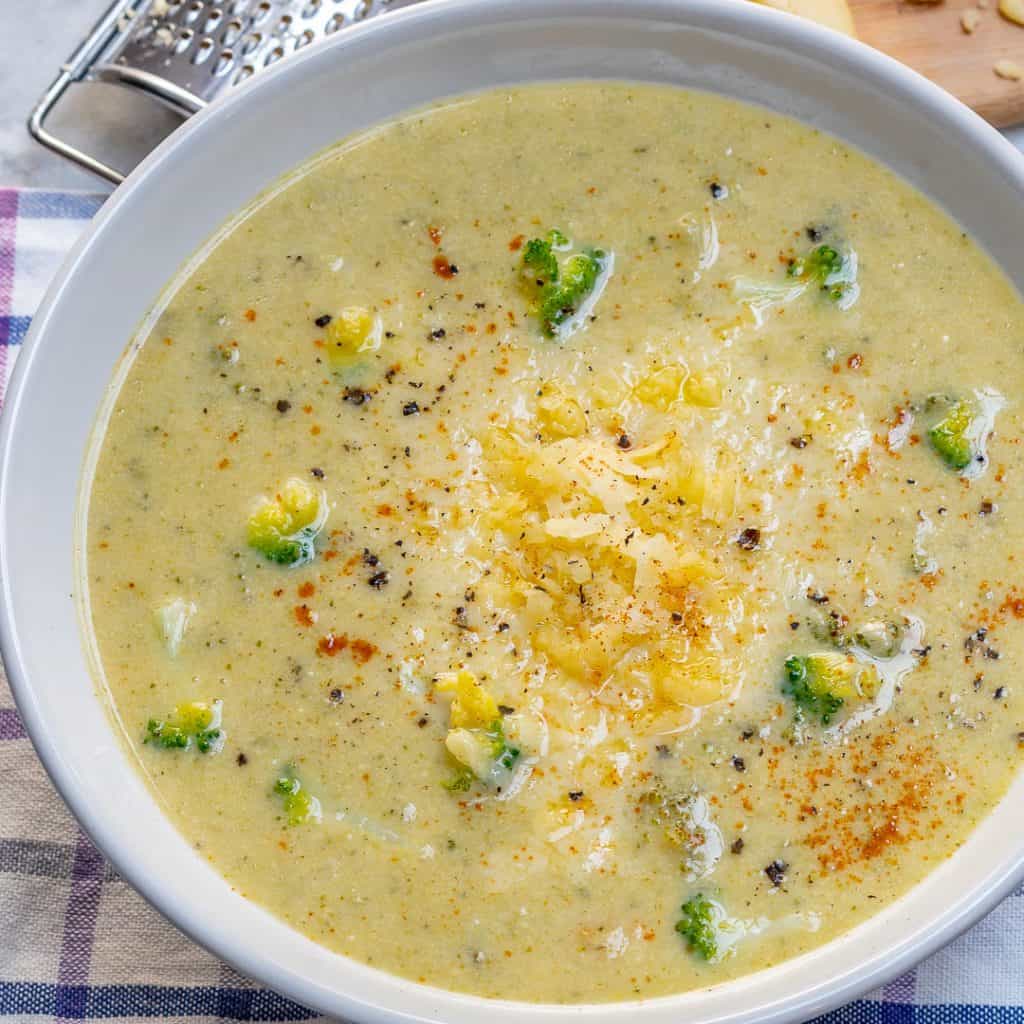 side view of a white bowl of Broccoli Cheddar Soup