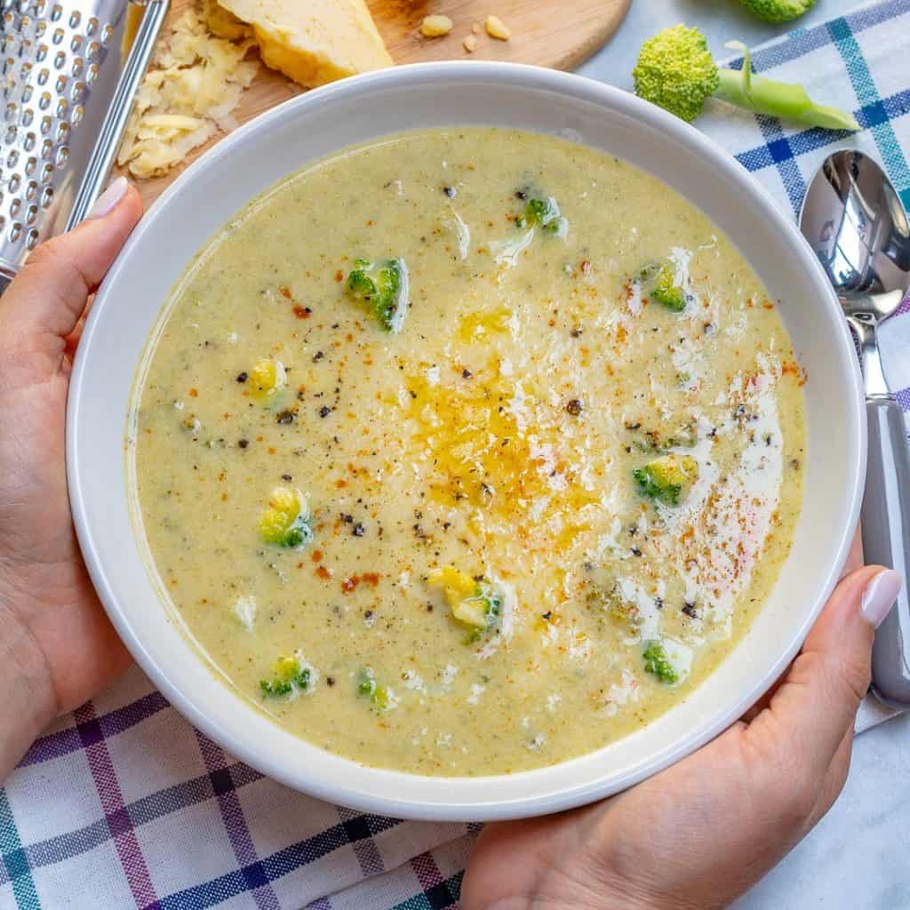 hand holding a bowl of healthy Broccoli cheddar Soup