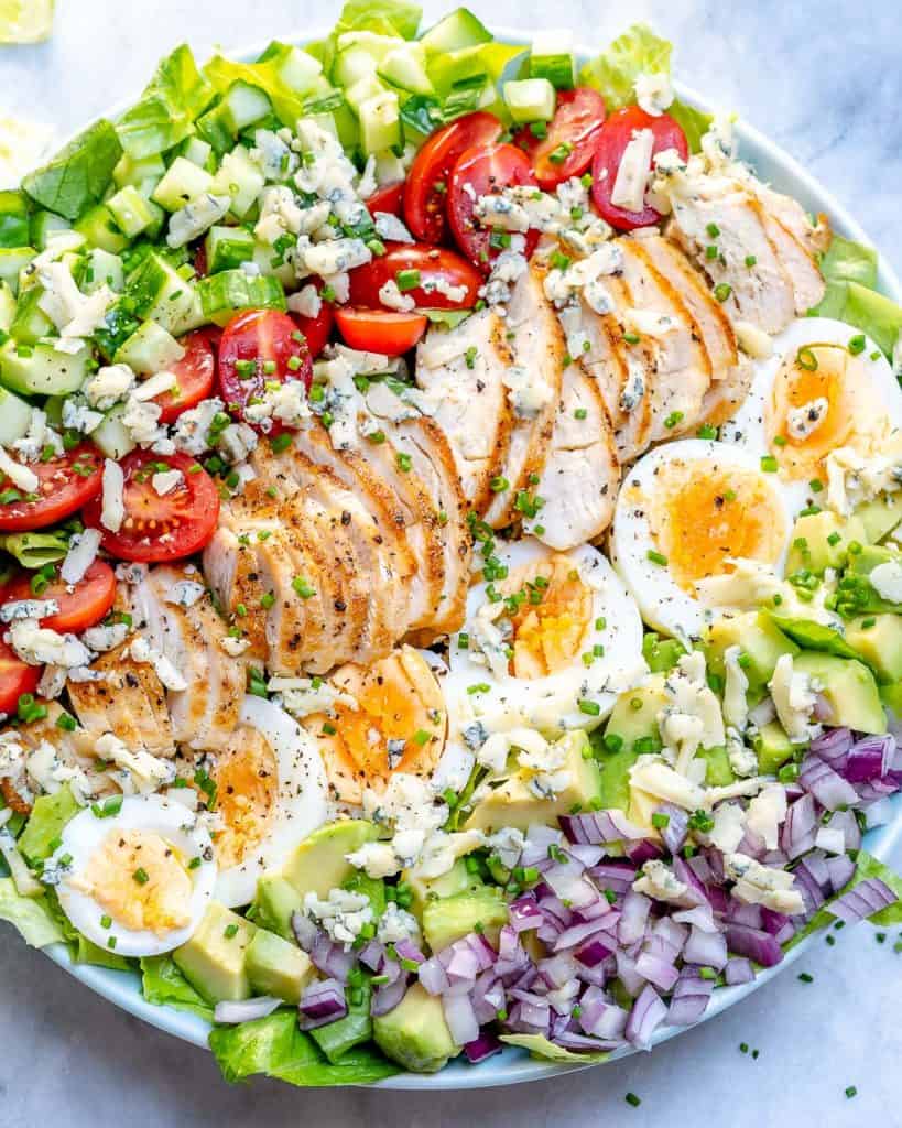 top close up view of chicken cobb salad with sliced boiled eggs and chopped veggies 