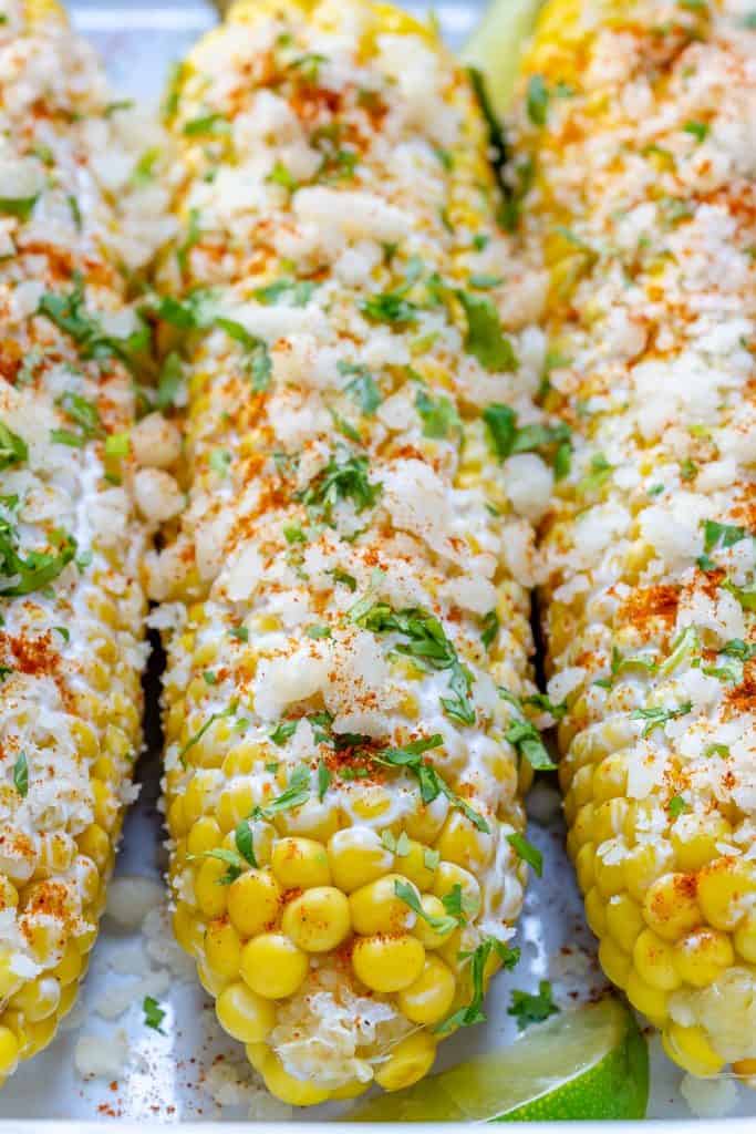 close up of Mexican street corn in a dish topped with crumbled cheese 