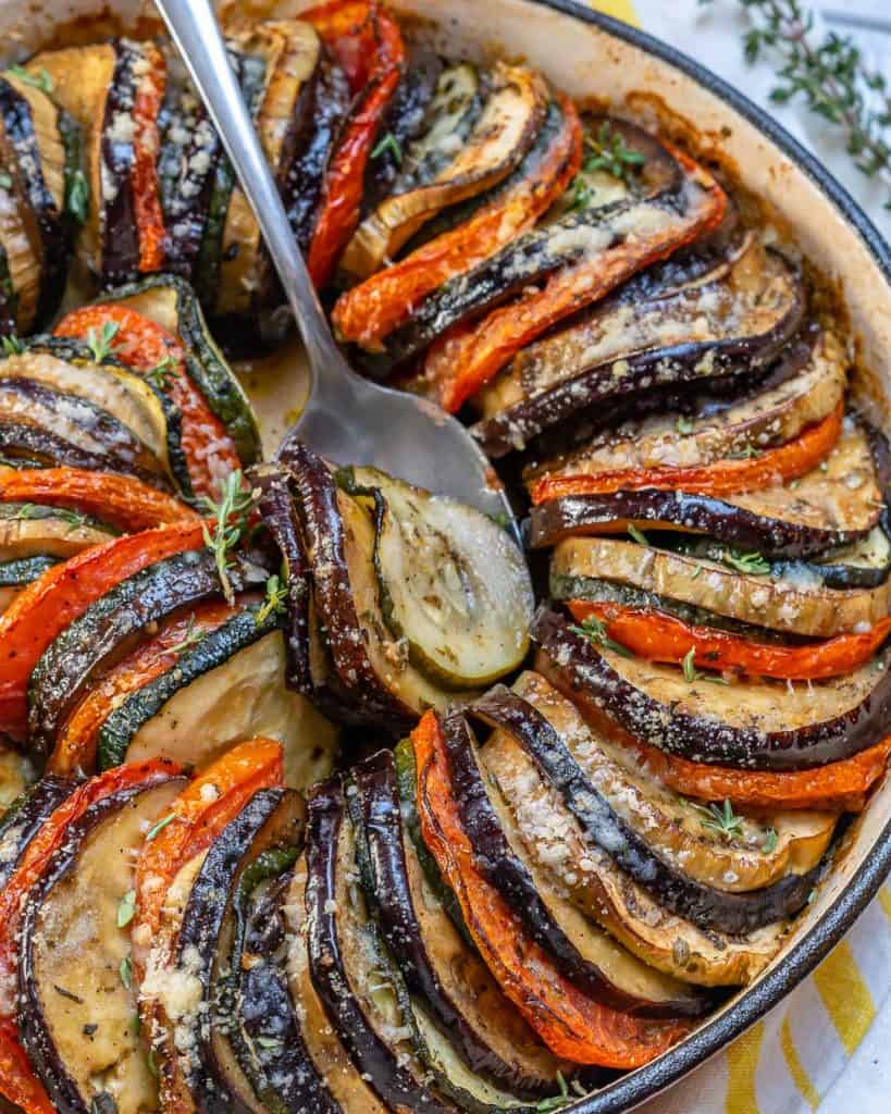 spoon in the dish veggies ratatouille made of slices of eggplant, zucchini, and tomatoes
