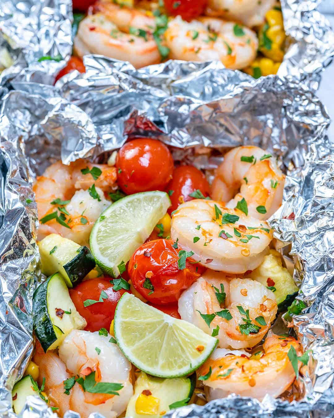 garlic butter shrimp recipe in a foil pack with vegetables and lime wedges