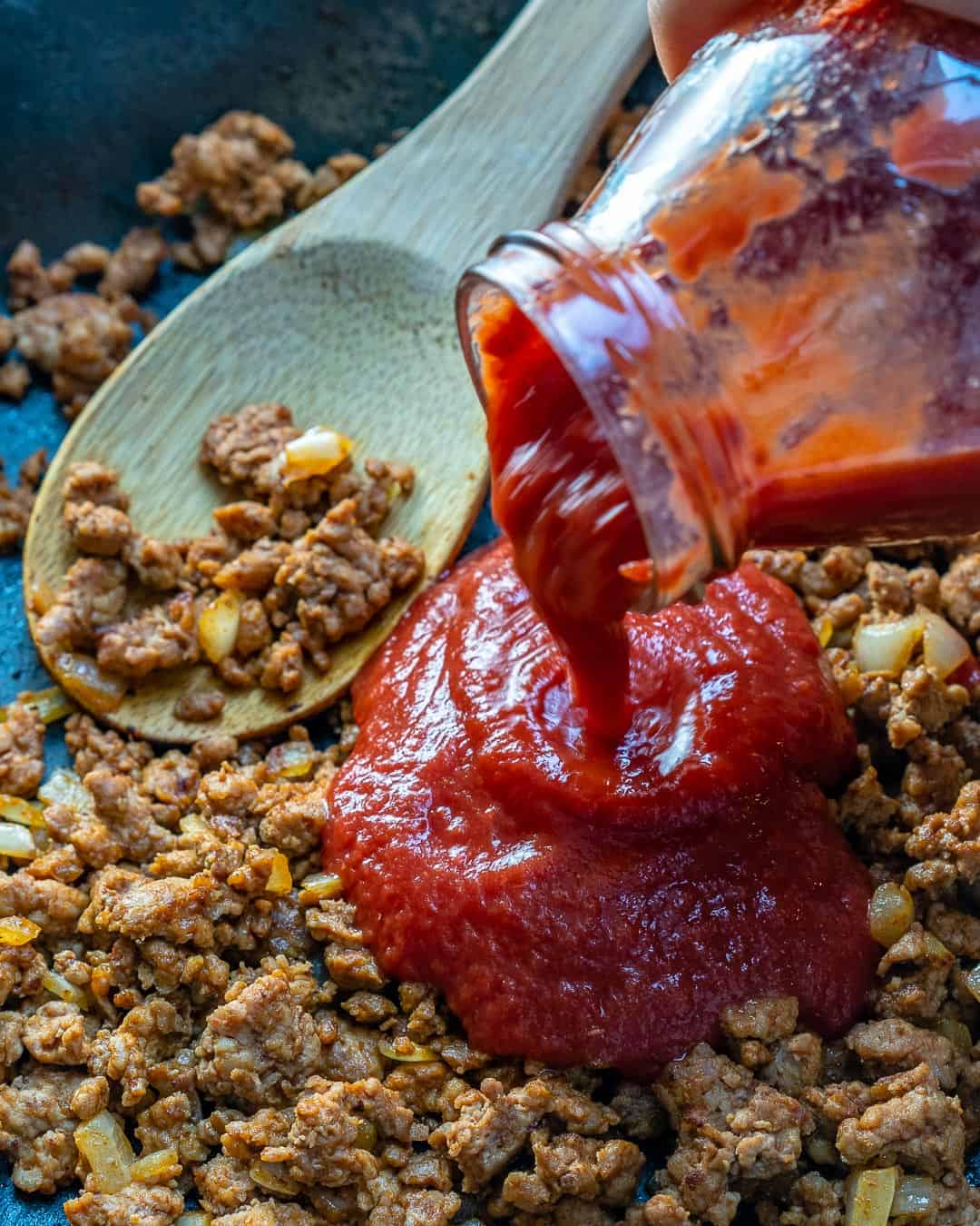 pouring tomatoes onto ground turkey