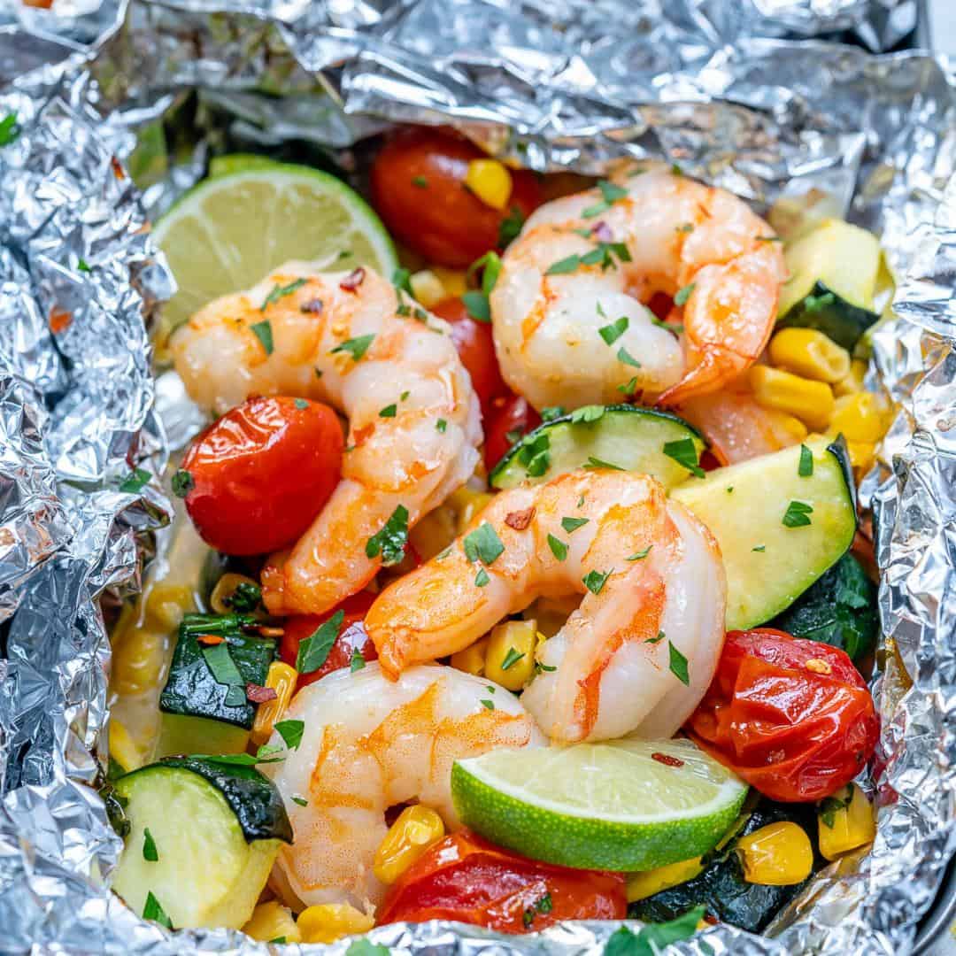 garlic butter shrimp in a foil pack with vegetables and lime wedges