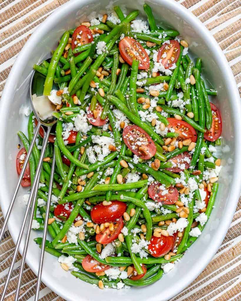 top view of green bean salad in a white bowl with feta cheese and cherry tomatoes 