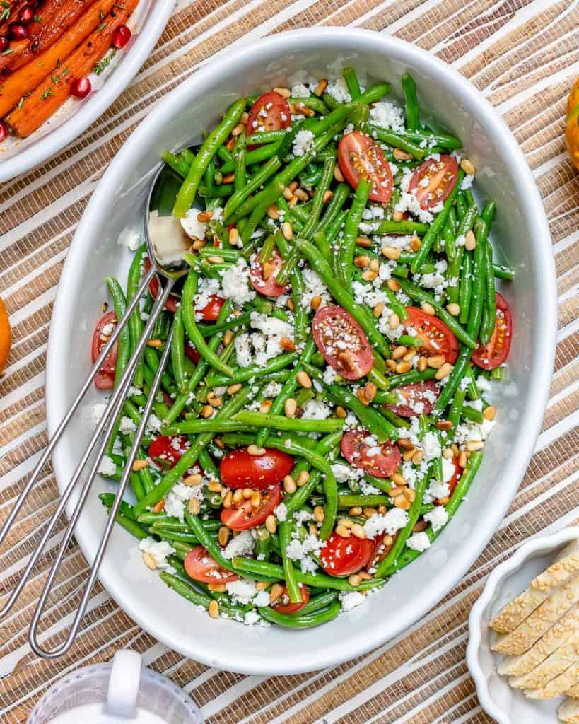 top view of green bean salad in a white bowl with feta cheese and cherry tomatoes 