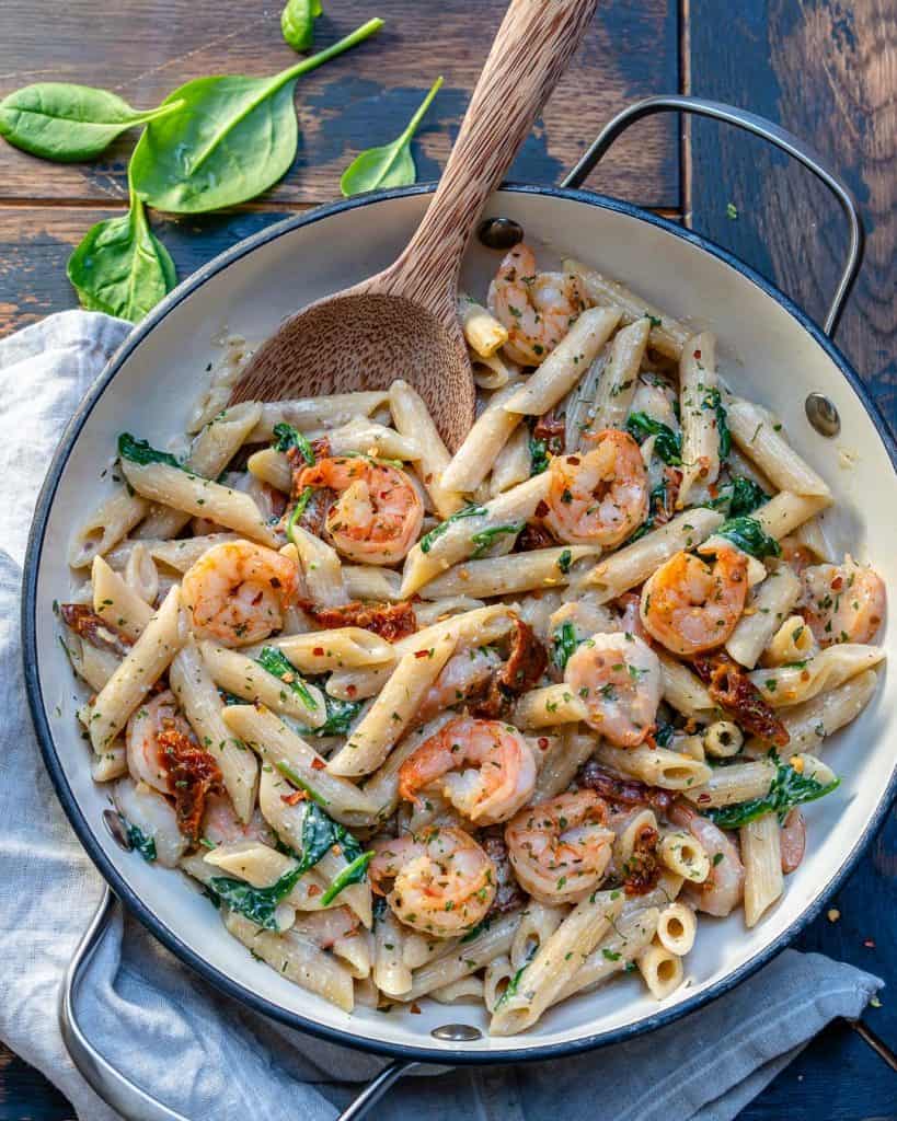 top view of a round skillet with creamy shrimp pasta made with added spinach