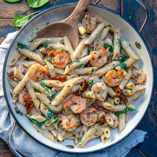 top view of a round skillet with whole wheat penne pasta made with shrimp