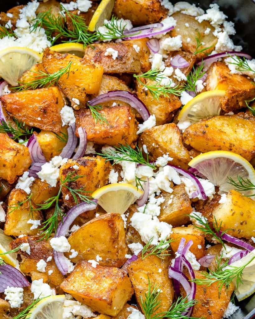 close up or roasted greek potatoes topped with feta cheese  onion and fresh dill
