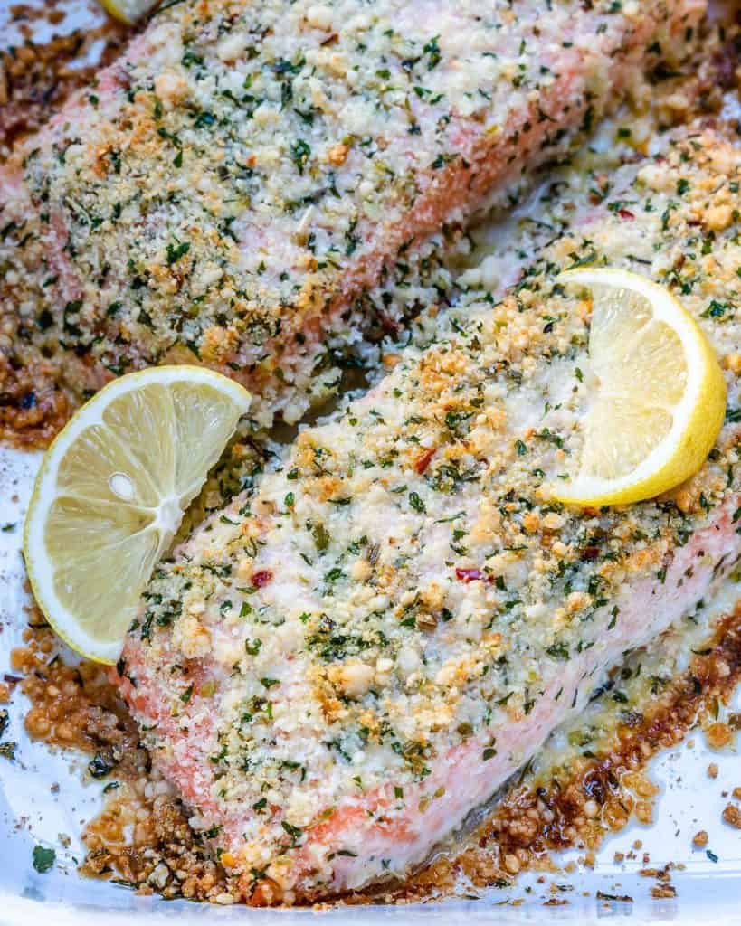 close up view of half baked salmon with parmesan crust and lemon slice garnish 
