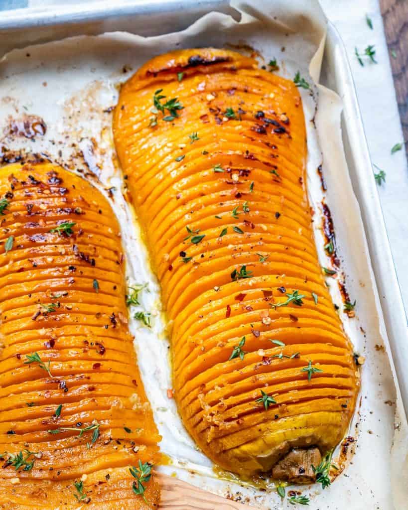 close up side shot of two Hasselback butternut squash on a baking pan